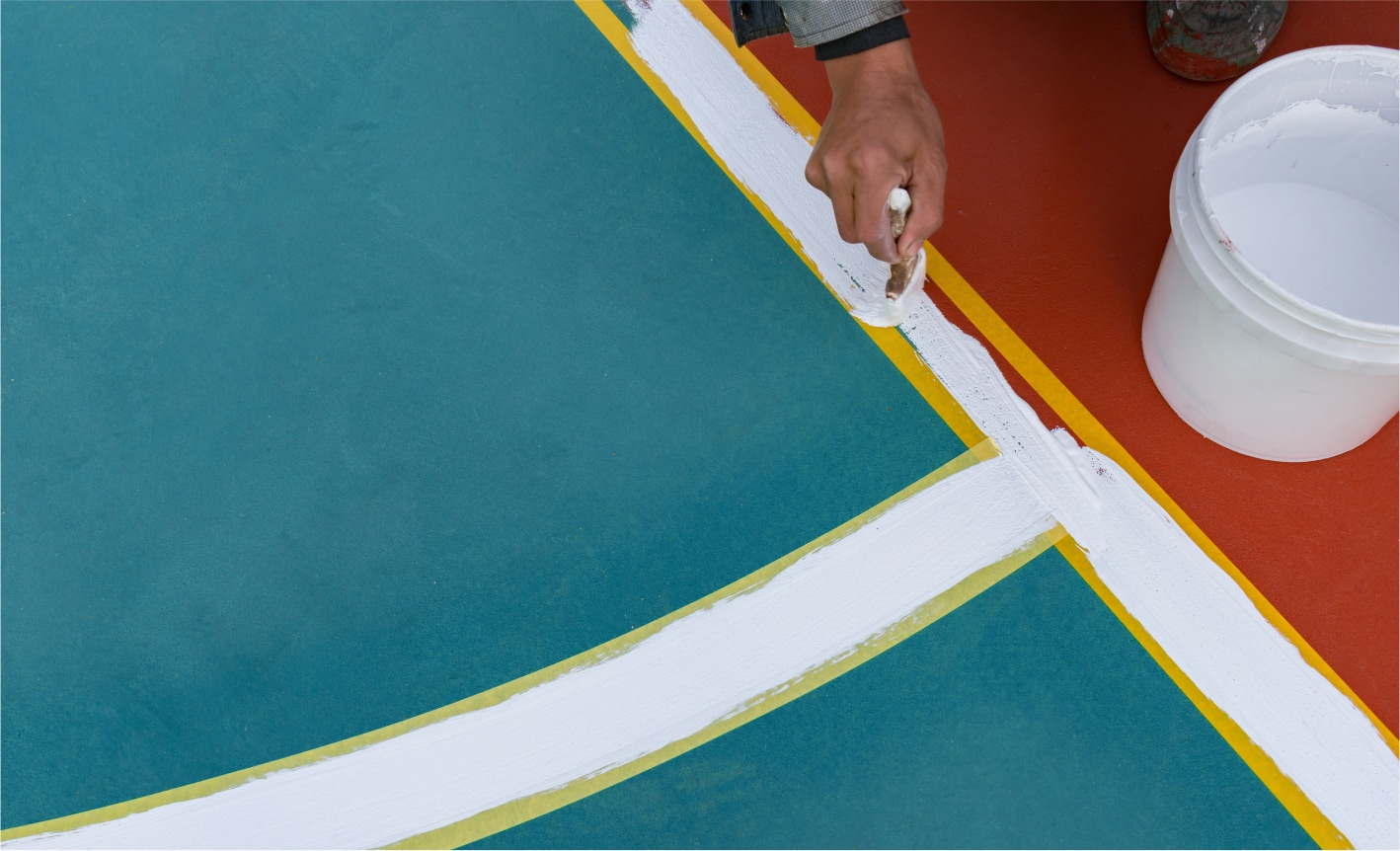 A hand painting lines on a sports ground